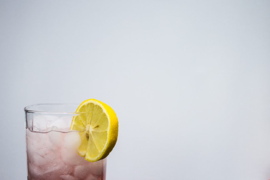 A pick cocktail in a small glass with a lemon wedge on the side