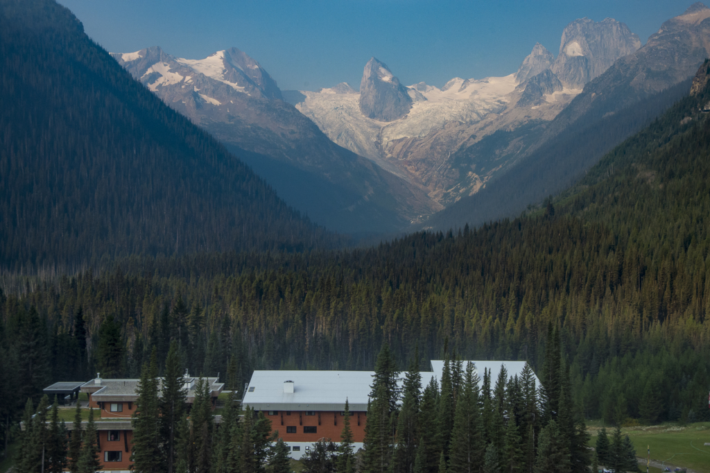 The remote CMH Bugaboo Lodge  sits within a green valley full of trees.