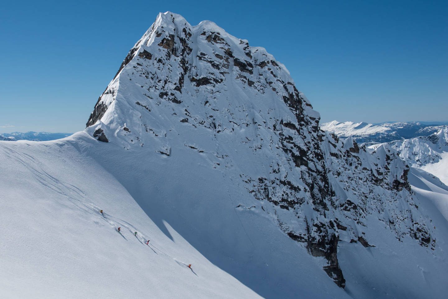 A group of heli-skiers skiing down a glacier outside of CMH Revelstoke.