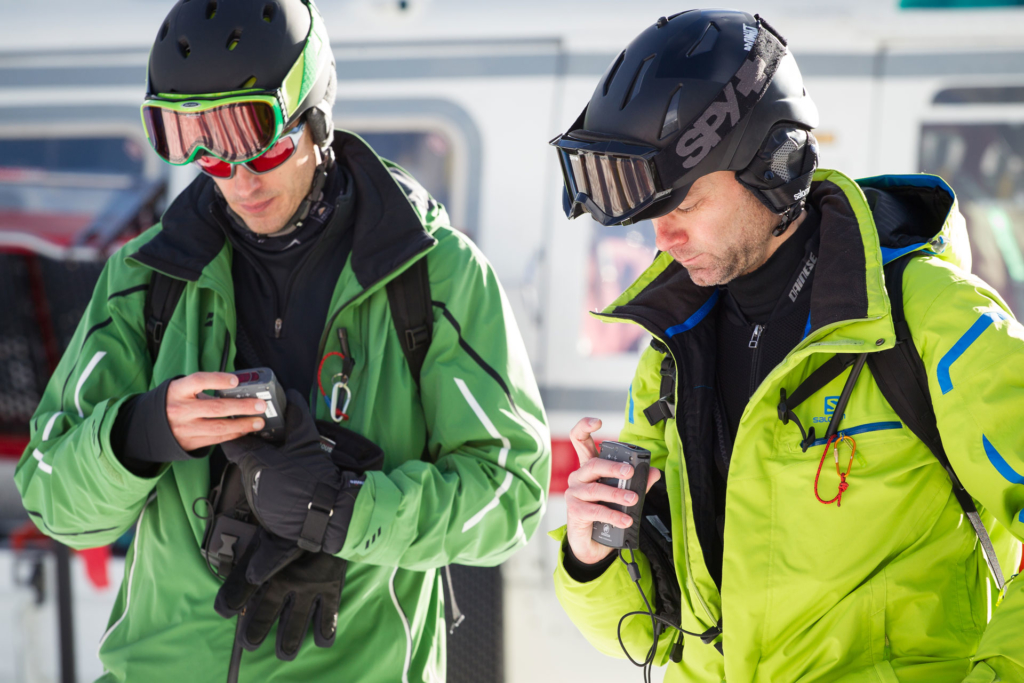 Two skiers looking at a transceiver