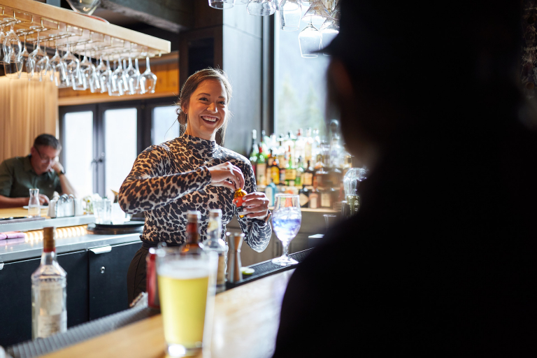 Smiling bartender servering a beverage