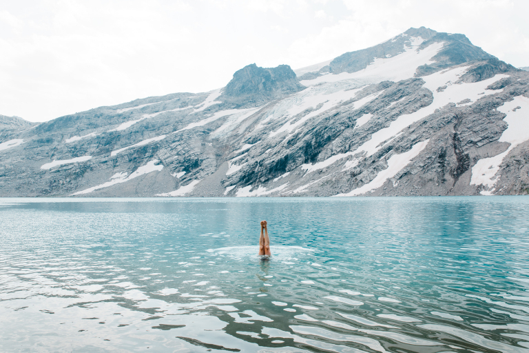 A hiker diving into a blue glacial lake.